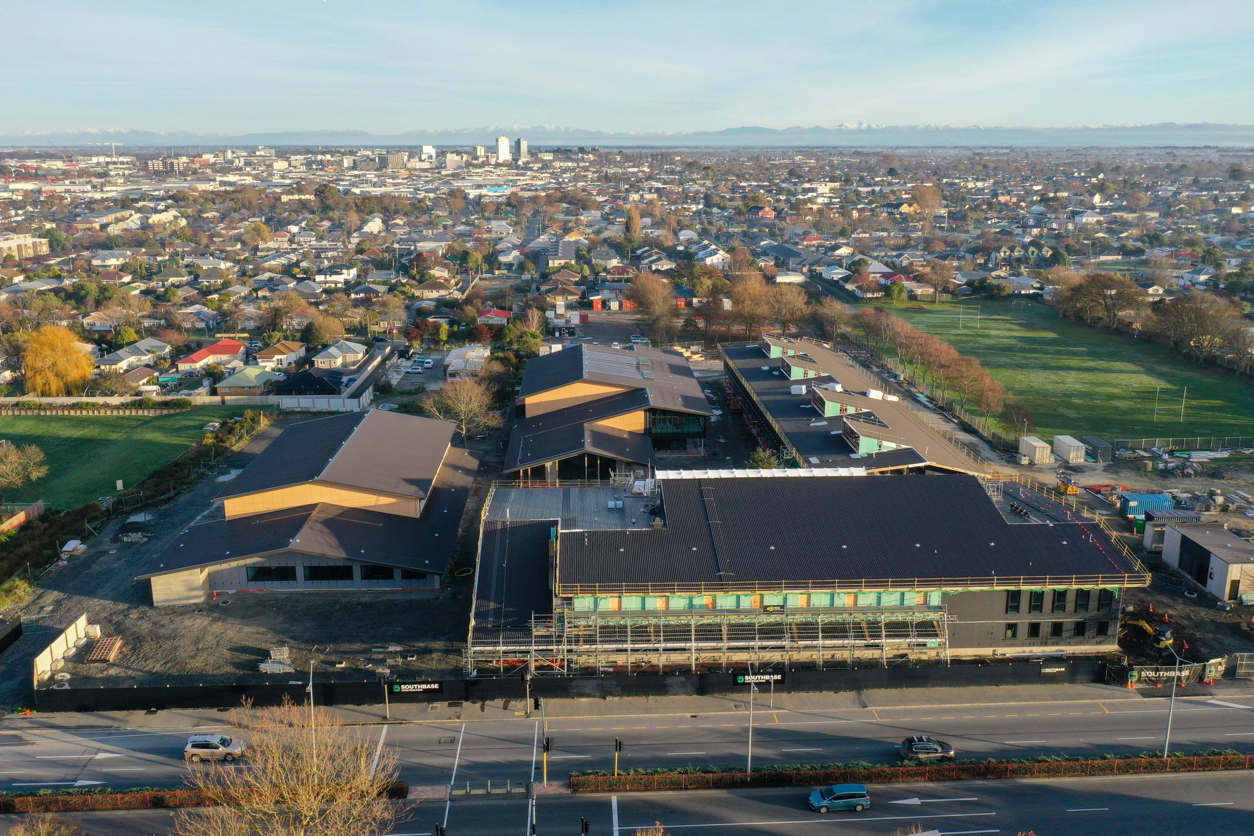 aerial photograph of Linwood College campus under construction with Christchurch city skyline in background. taken at sunrise with mountains visible