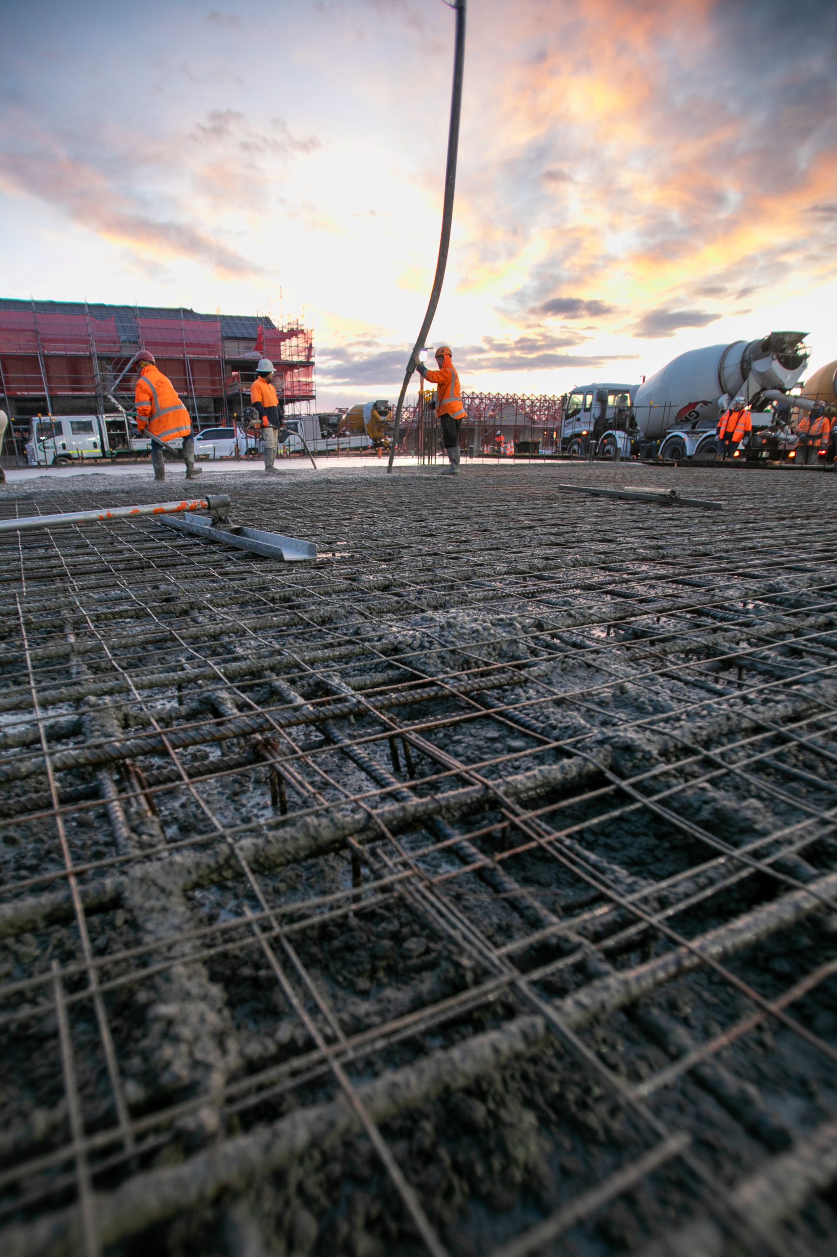 Construction site foundation with rebar steel and concrete at sunrise with colors and workers. Videography by Upsite
